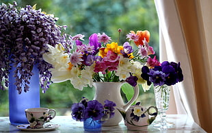 white, purple, and orange Wisteria and petaled flowers in vases